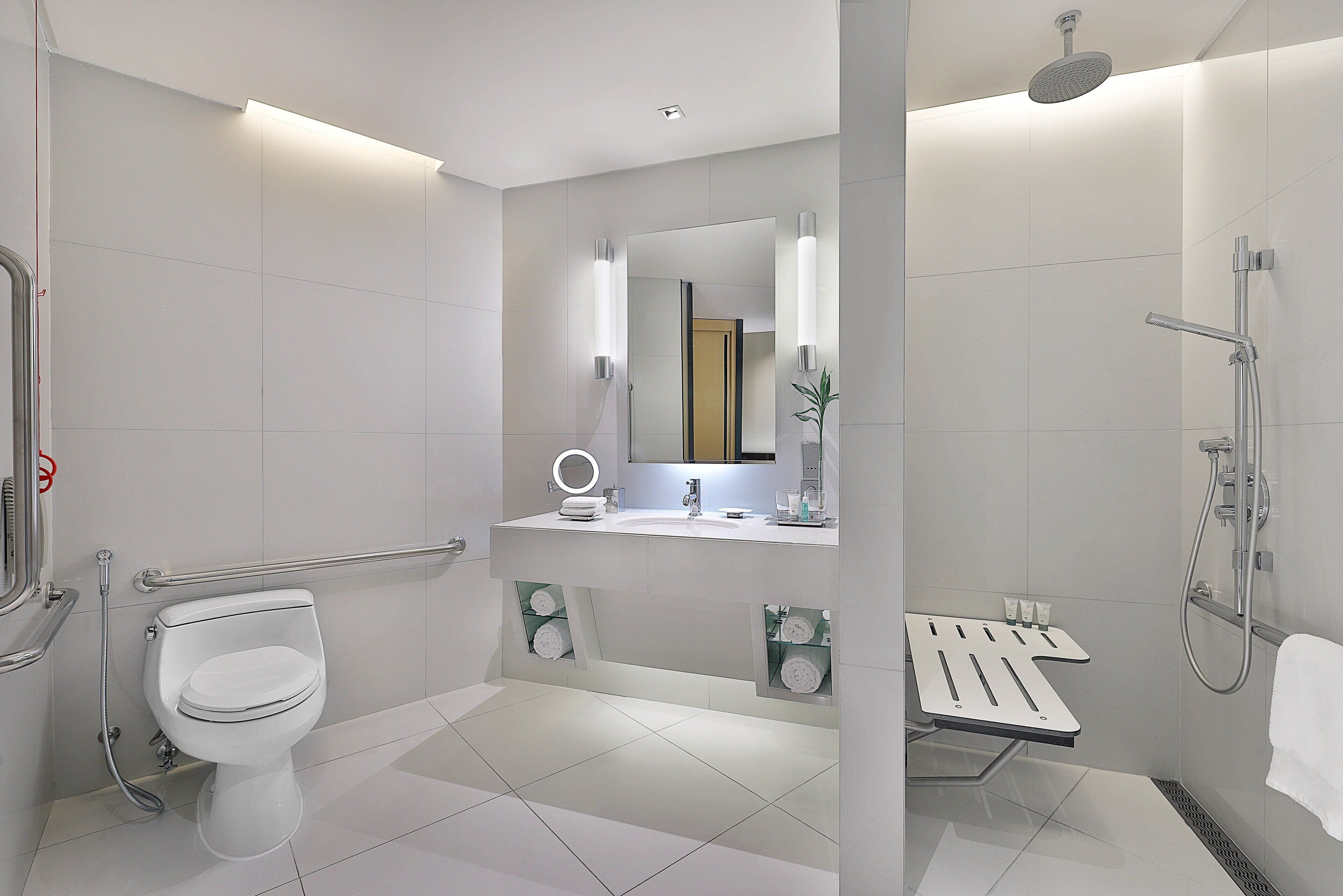 A modern bathroom with a toilet, sink, mirror, towel rack, and shower.