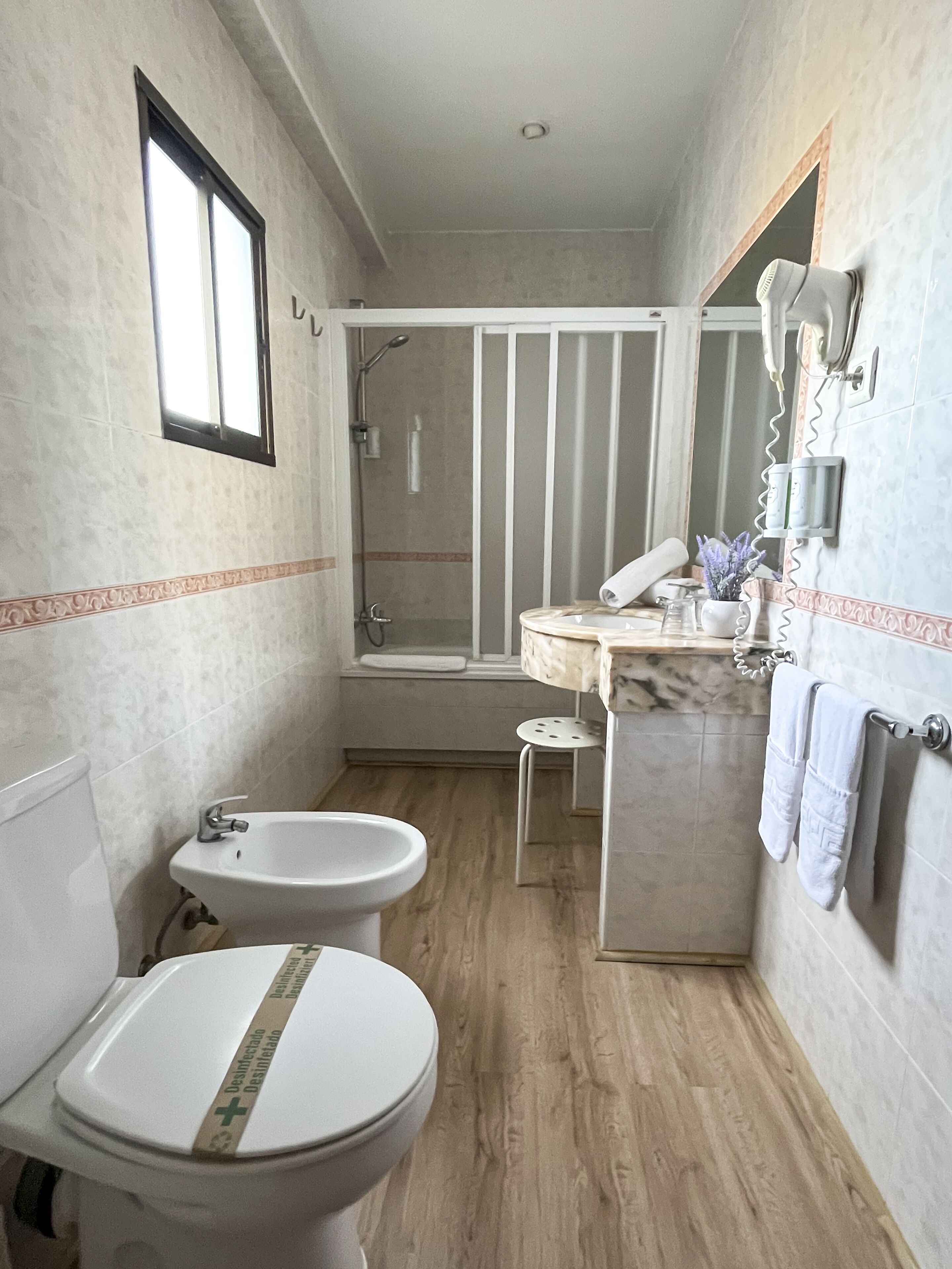 Een badkamer met toilet, bidet, wastafel en douche.