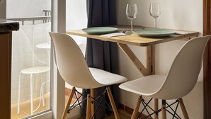 Un comedor con una mesa de madera, dos sillas blancas y dos copas de vino.