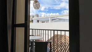 Un balcón con mesa y sillas, una lámpara colgante y vistas de la ciudad.