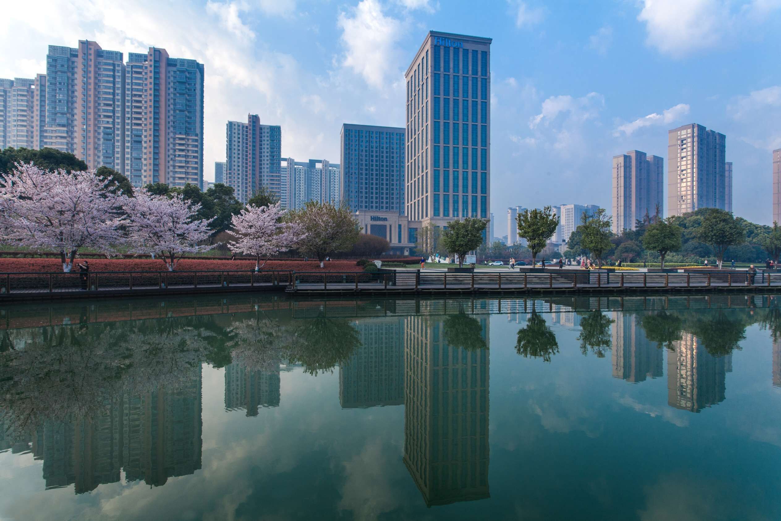 Un paisaje urbano con edificios altos y una masa de agua tranquila que refleja las construcciones.