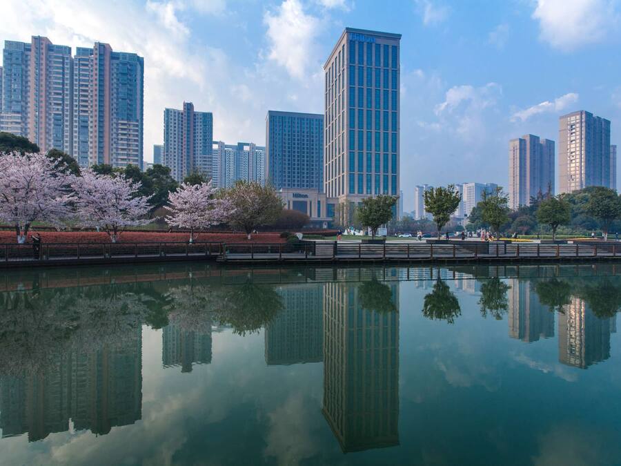 Un paisaje urbano con edificios altos y una masa de agua tranquila que refleja las construcciones.