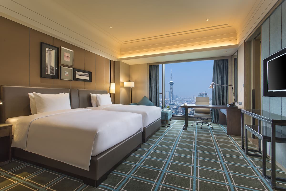 Une chambre d’hôtel avec un grand lit, un bureau et une vue sur le paysage urbain.