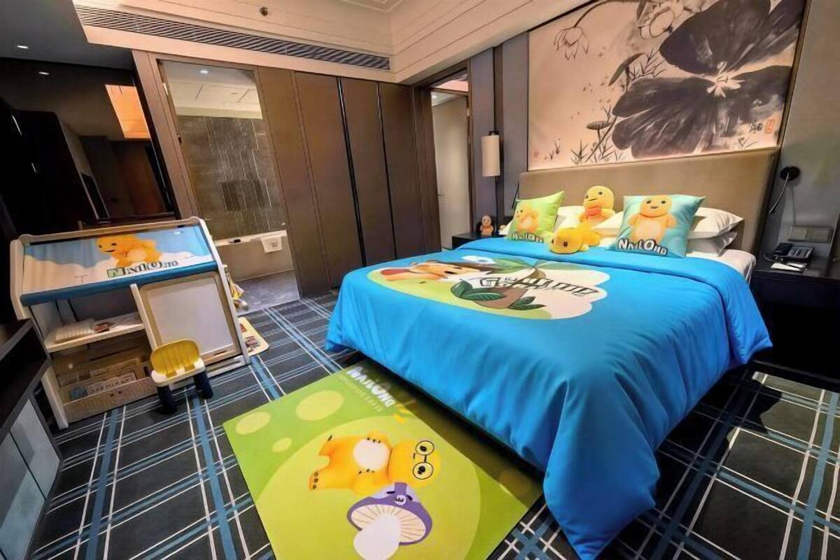 Une chambre d’hôtel avec un grand lit, un bureau avec un ordinateur et une vue sur l’extérieur.