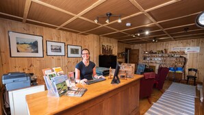 A wooden-paneled reception area with a desk, computer, and framed pictures on the wall. - Auberge Le Four à Pain (Petite-Riviere-Saint-Francois)