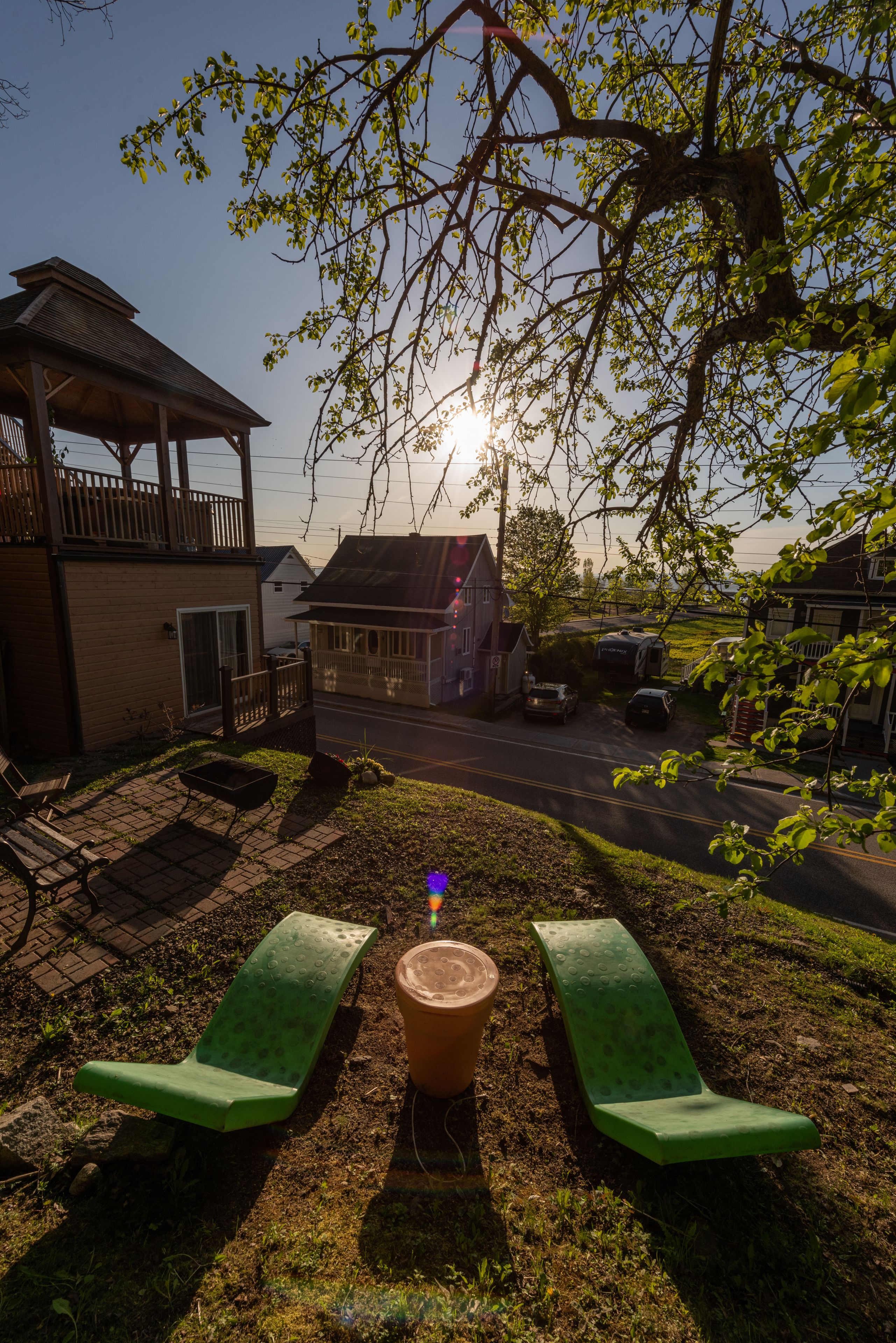 A patio with two green benches, a wooden pergola, and a house in the background.