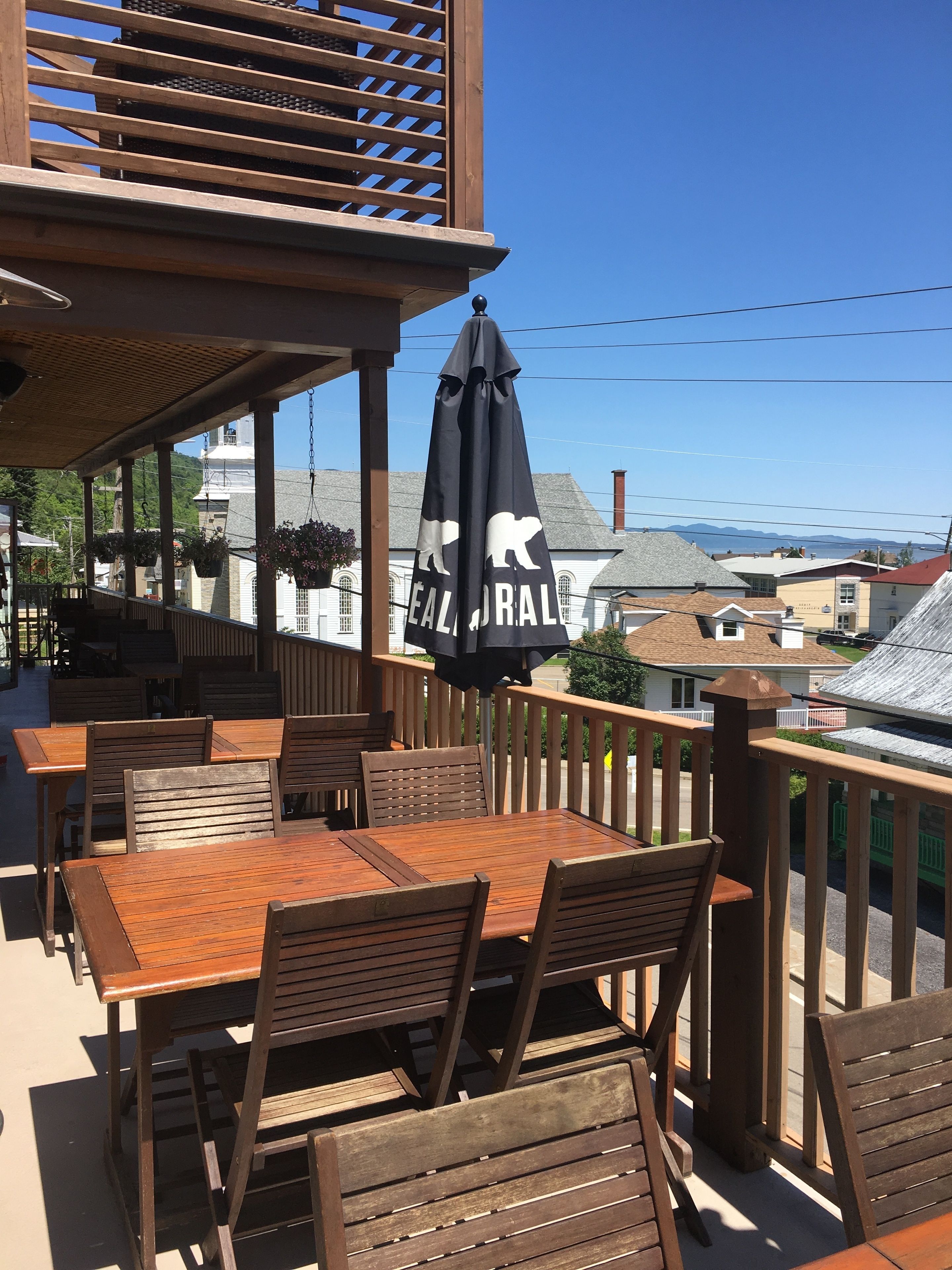 A wooden deck with outdoor seating, including tables and chairs, and a hanging umbrella.