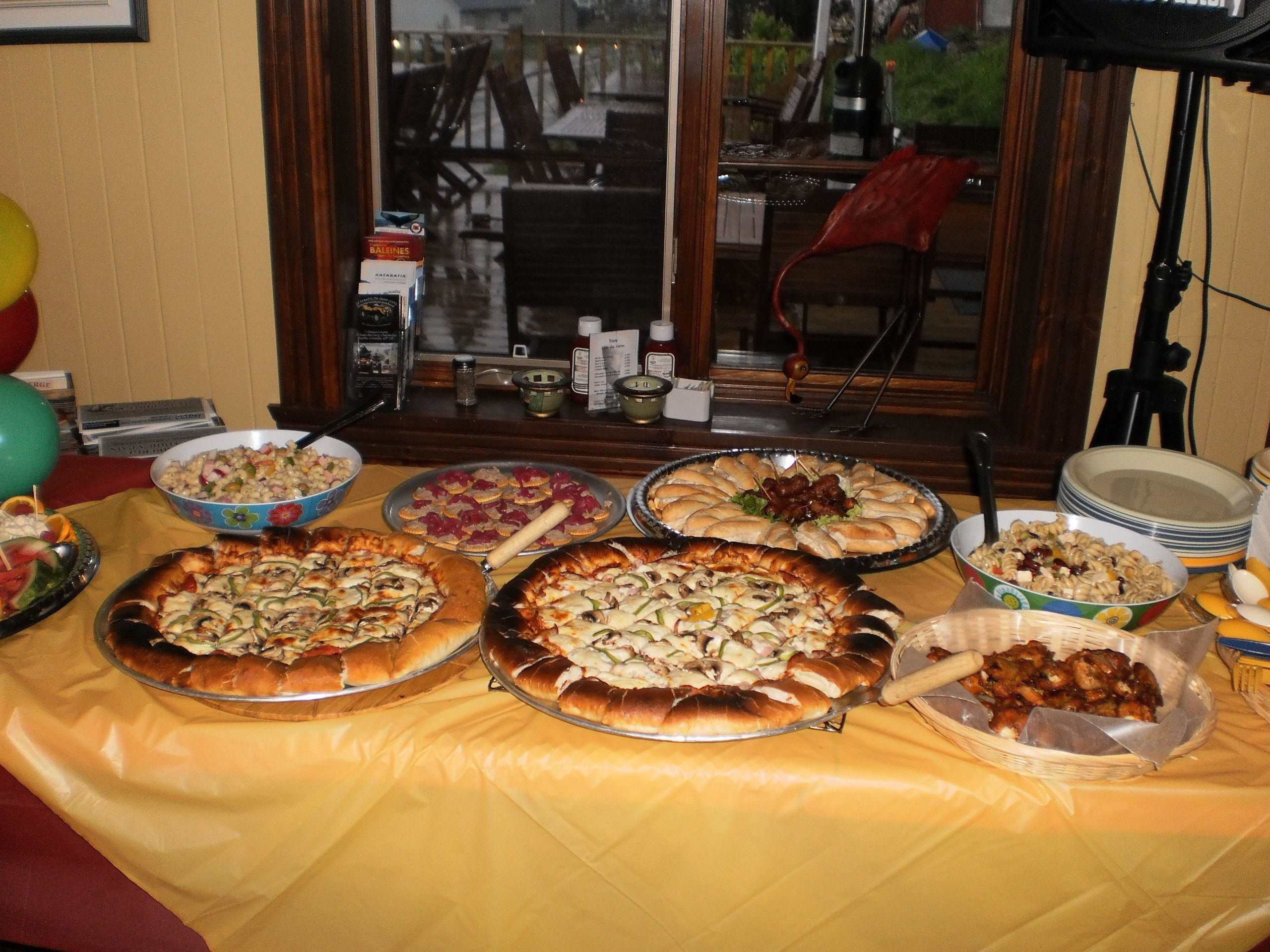 Una mesa con diversas pizzas y acompañamientos, probablemente dispuesta para una reunión o fiesta.