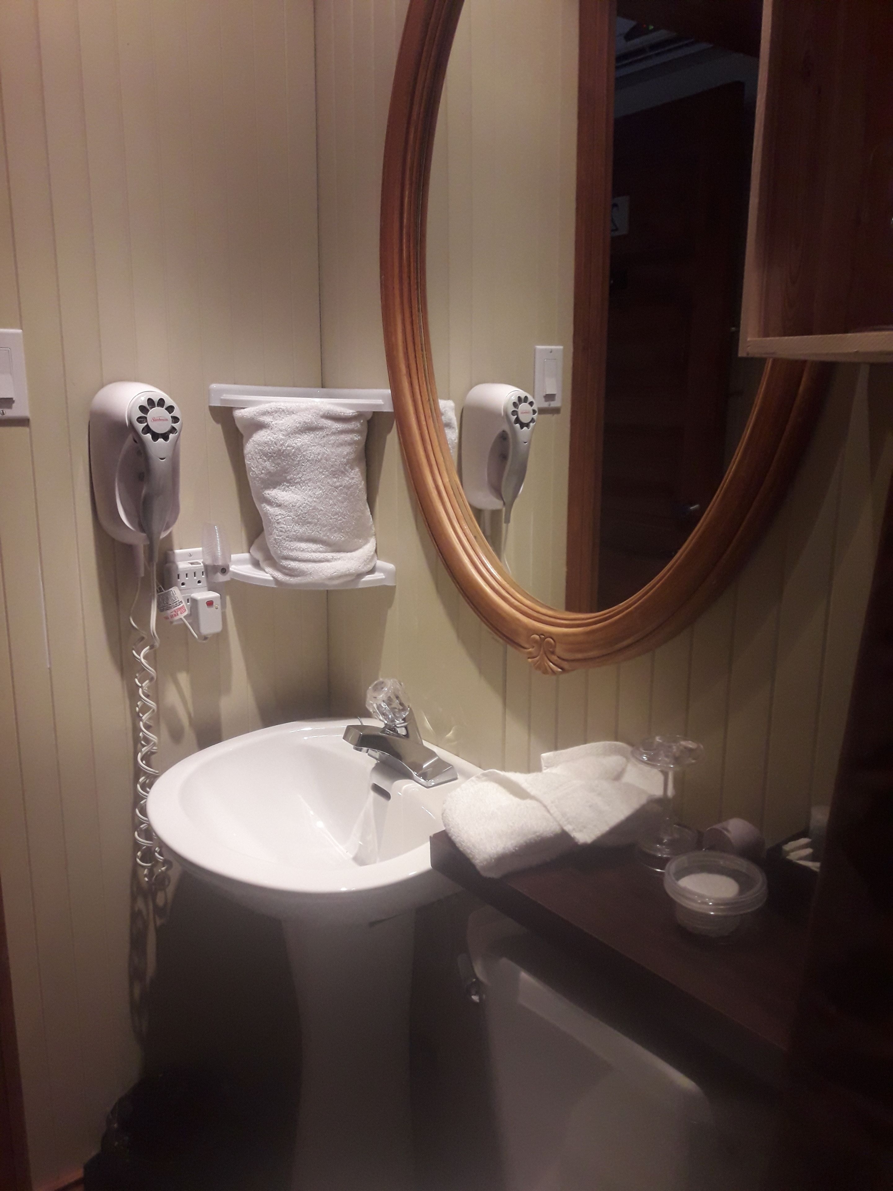 Un bagno con lavandino, specchio, asciugamano e due asciugacapelli.
