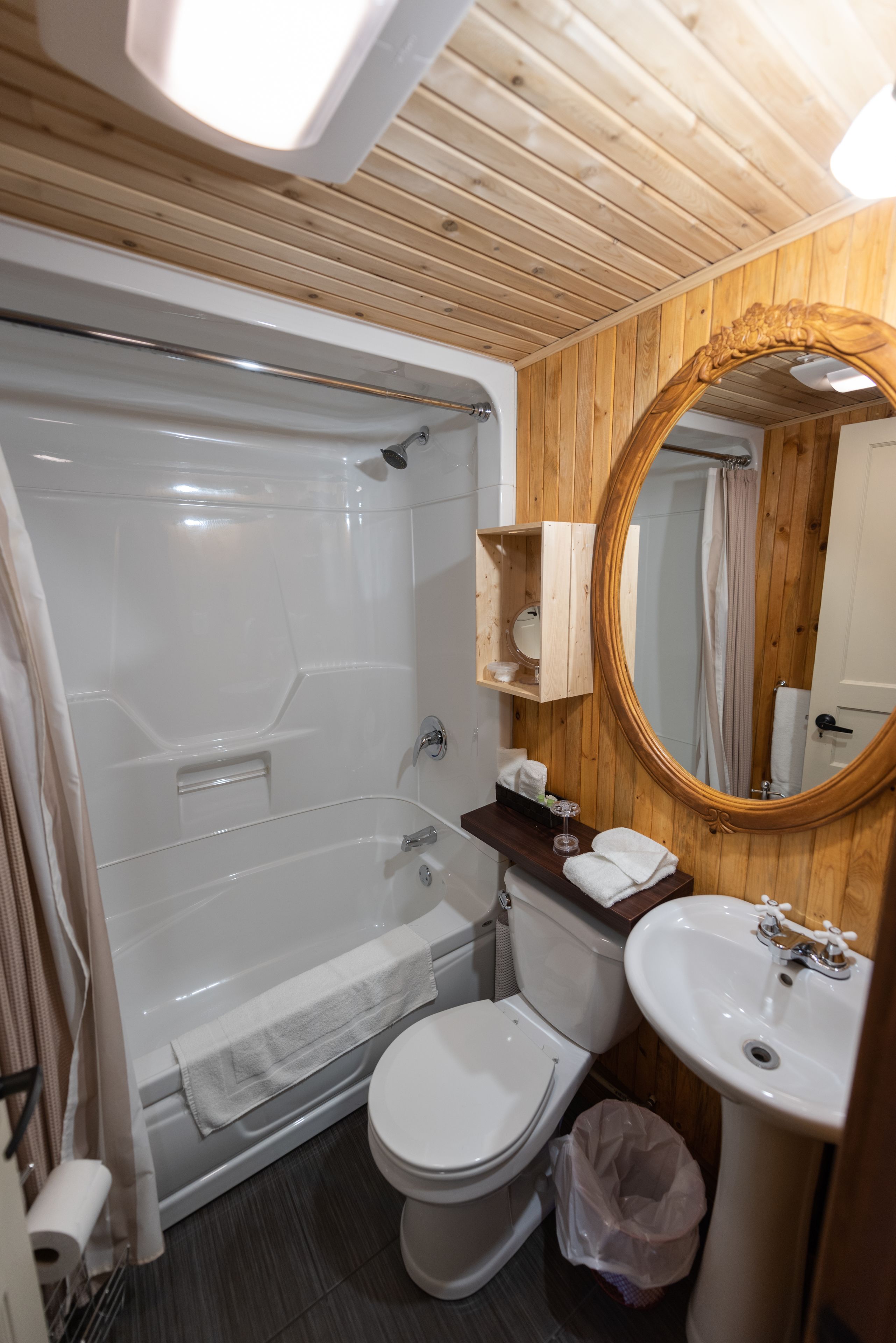 Un baño con bañera, inodoro, lavamanos y paneles de madera.