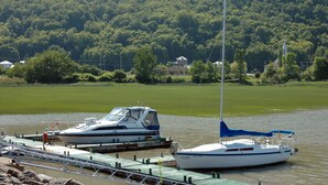 A marina with a sailboat docked at a pier, surrounded by a forested area. - Auberge Le Four à Pain (Petite-Riviere-Saint-Francois)