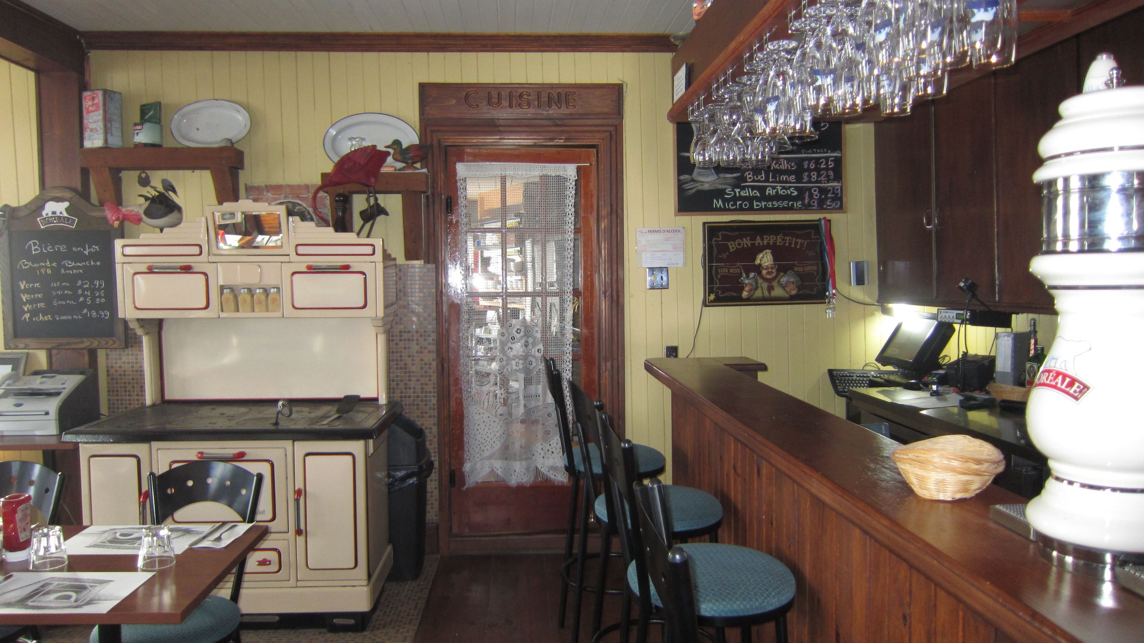 A bar area with a vintage counter, stools, and a chalkboard menu.