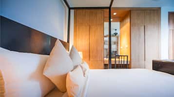 A modern hotel room with a neatly made bed, a wooden wardrobe, and a desk with a chair.
