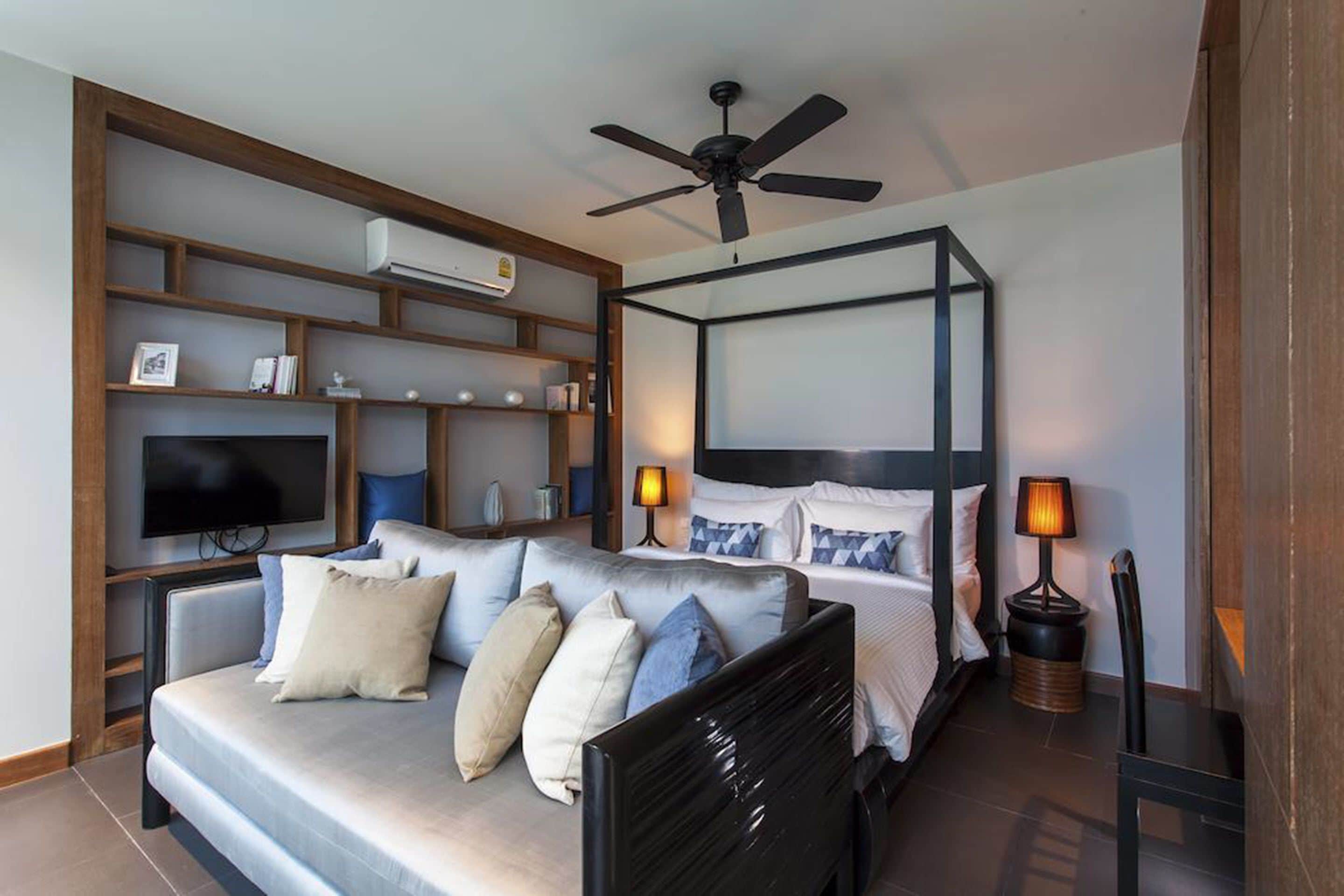 Une chambre moderne avec un lit, un canapé, une télévision et un ventilateur de plafond.