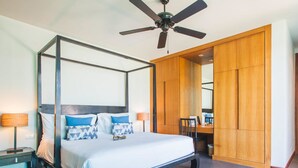 Un lit à baldaquin avec un ventilateur de plafond, une armoire en bois et un bureau avec une chaise.