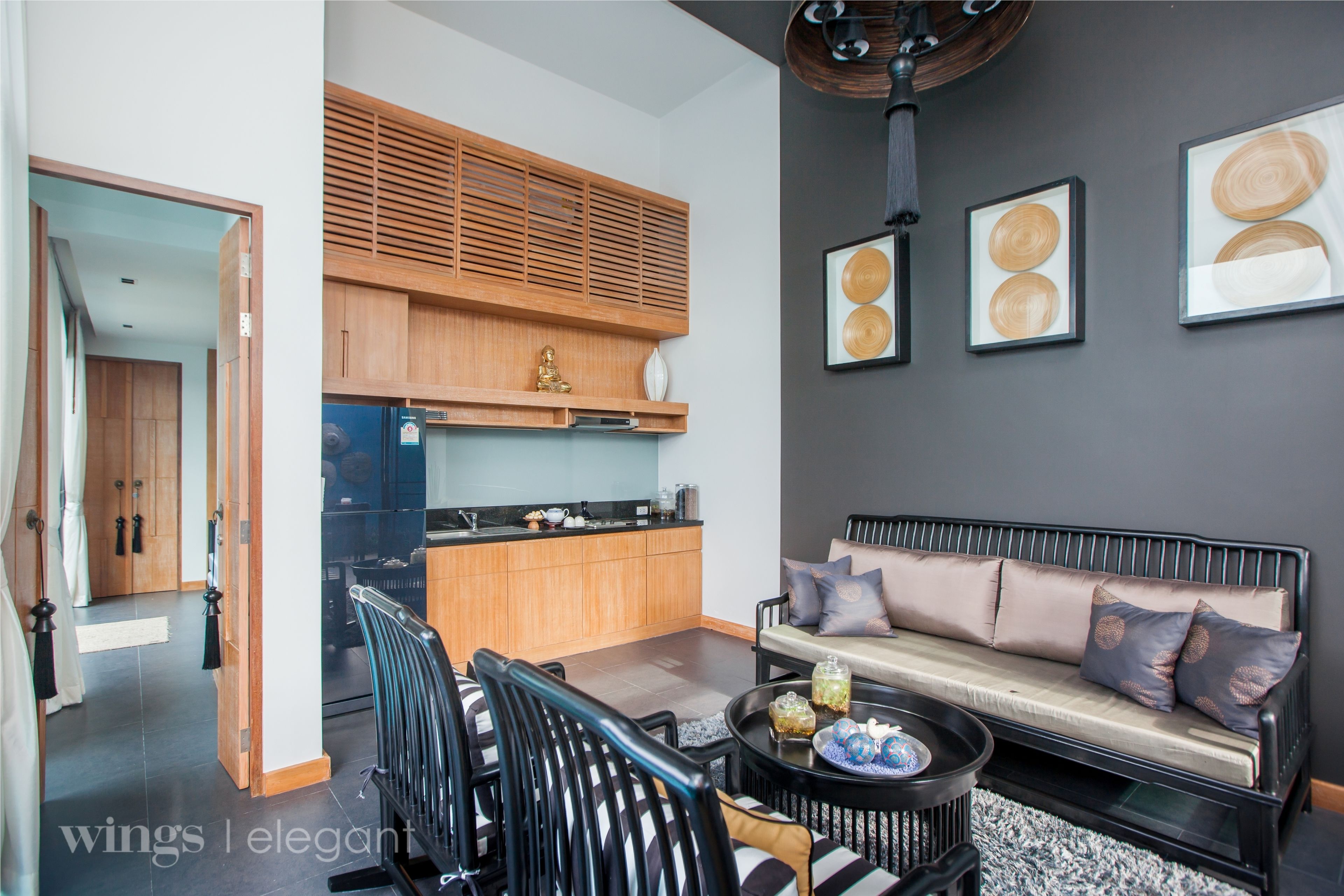 A modern living room with a sofa, coffee table, and chairs. There is a kitchen area with wooden cabinets and a countertop.
