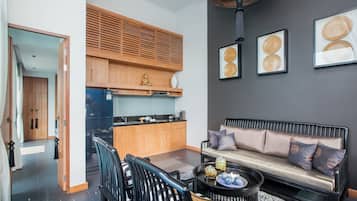 A modern living room with a sofa, coffee table, and chairs. There is a kitchen area with wooden cabinets and a countertop.