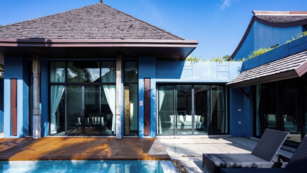 Une maison moderne dotée d’une piscine, de grandes portes vitrées et de mobilier d’extérieur.