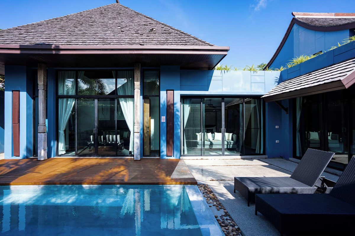 Une maison moderne dotée d’une piscine, de grandes portes vitrées et de mobilier d’extérieur.