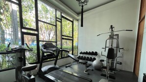 Une salle de sport équipée d’un tapis de course, d’un banc de musculation, d’haltères et d’un vélo d’appartement.