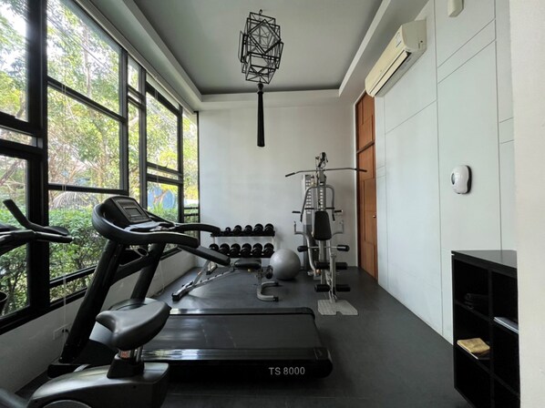 Une salle de sport équipée d’un tapis de course, d’haltères et d’un vélo d’appartement.
