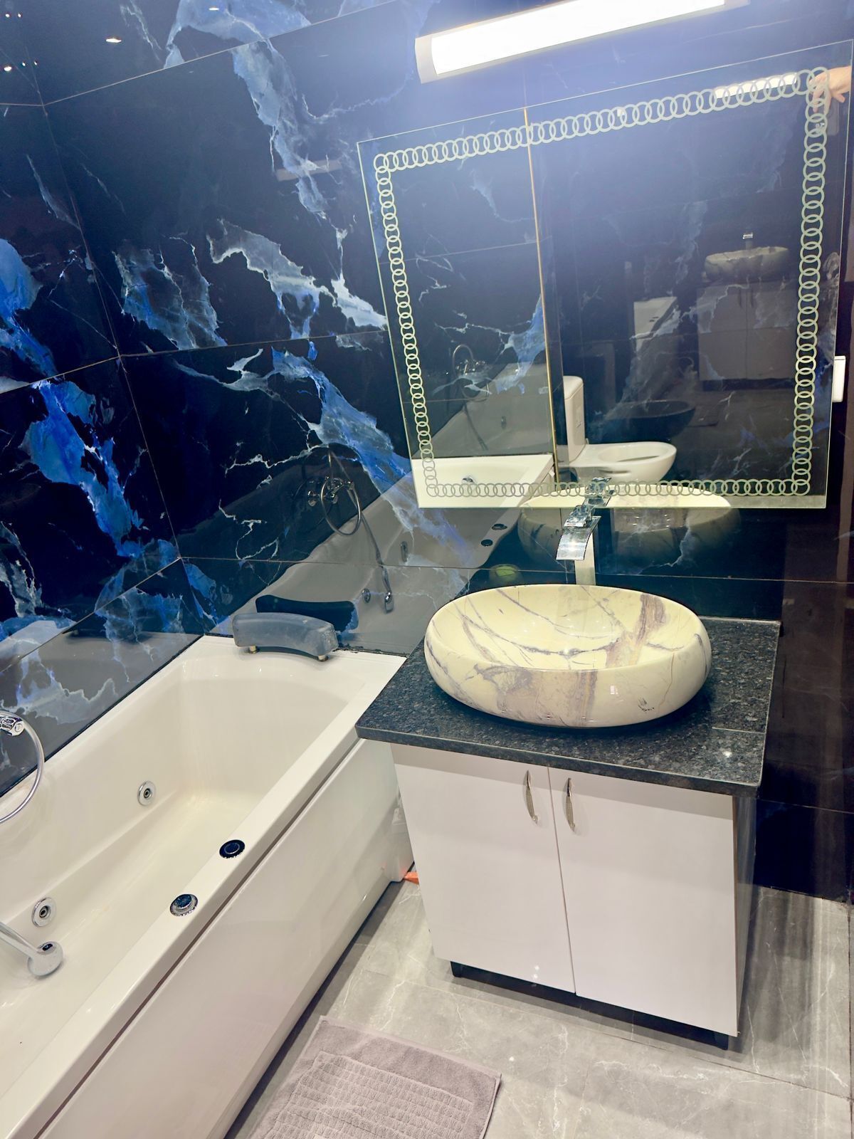 Un bagno moderno con un mobile vanitario in marmo, una vasca freestanding e uno specchio grande.