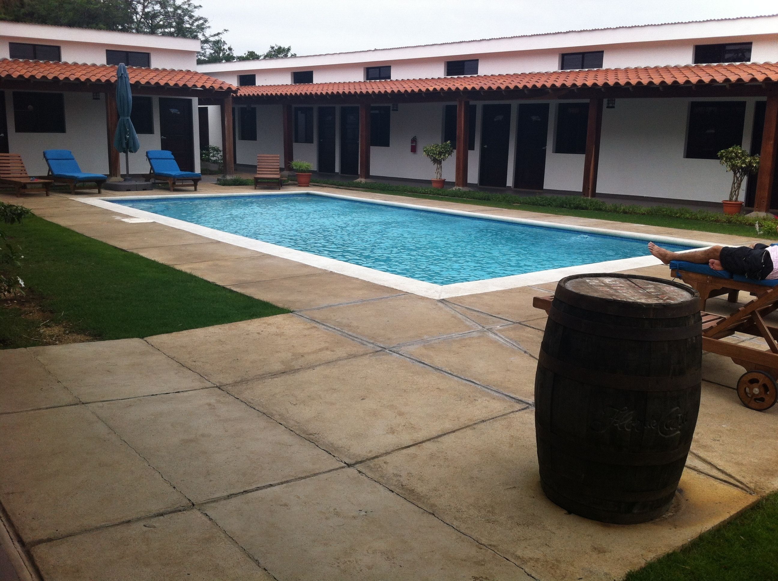 Una piscina con sillas de descanso y un barril de madera.