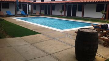 Una piscina con sillas de descanso y un barril de madera.