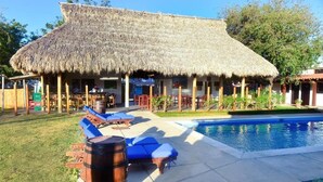 A thatched-roof building with outdoor seating and a pool. - Machele' s Place Beachside Hotel & Pool (Tola)
