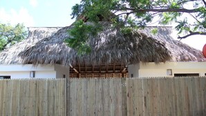 A thatched-roof structure with a wooden fence in front. - Machele' s Place Beachside Hotel & Pool (Tola)