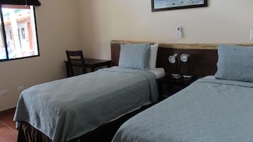 Habitación de hotel con dos camas, un escritorio y una silla.