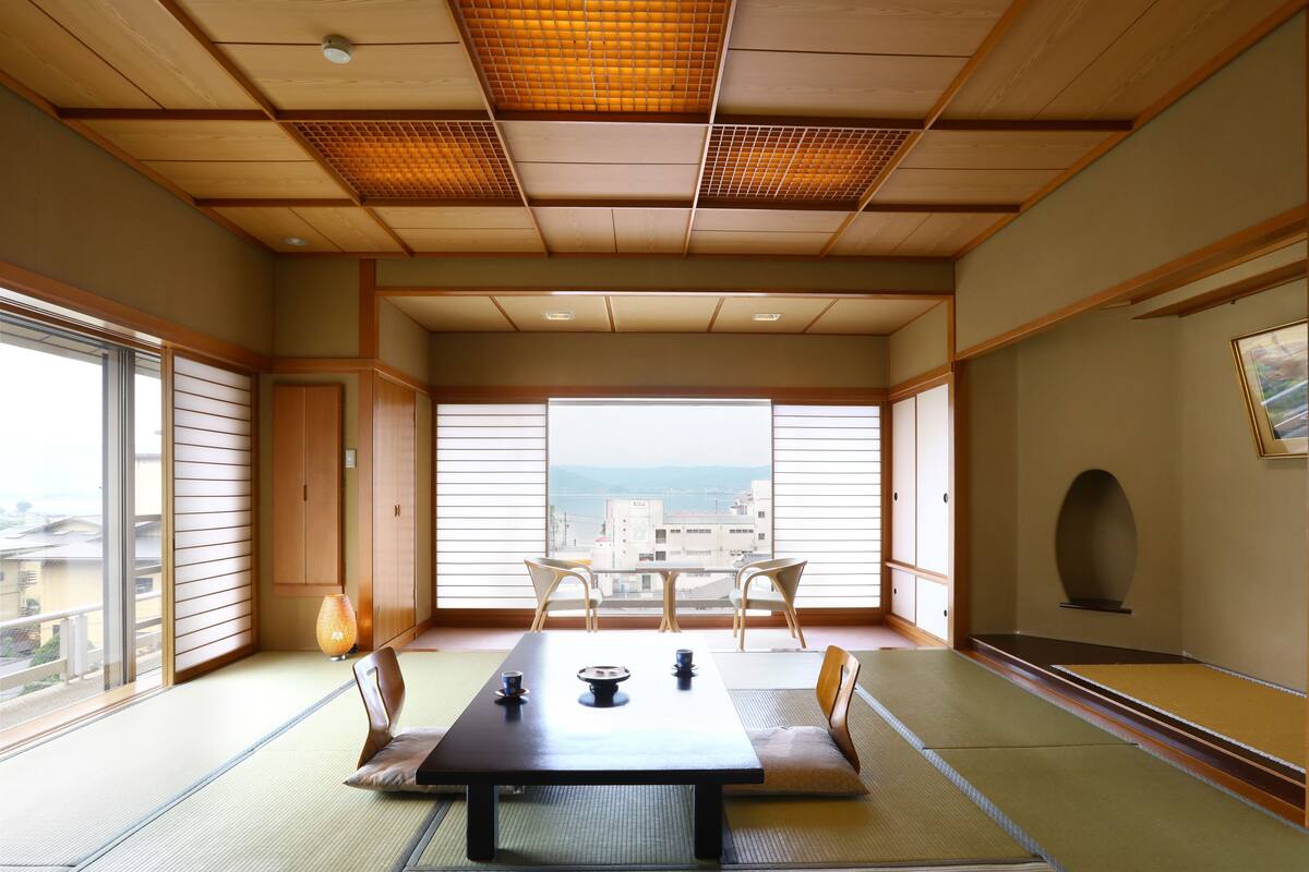 Una habitación tradicional japonesa con suelo de tatami, una mesa baja y puertas correderas.