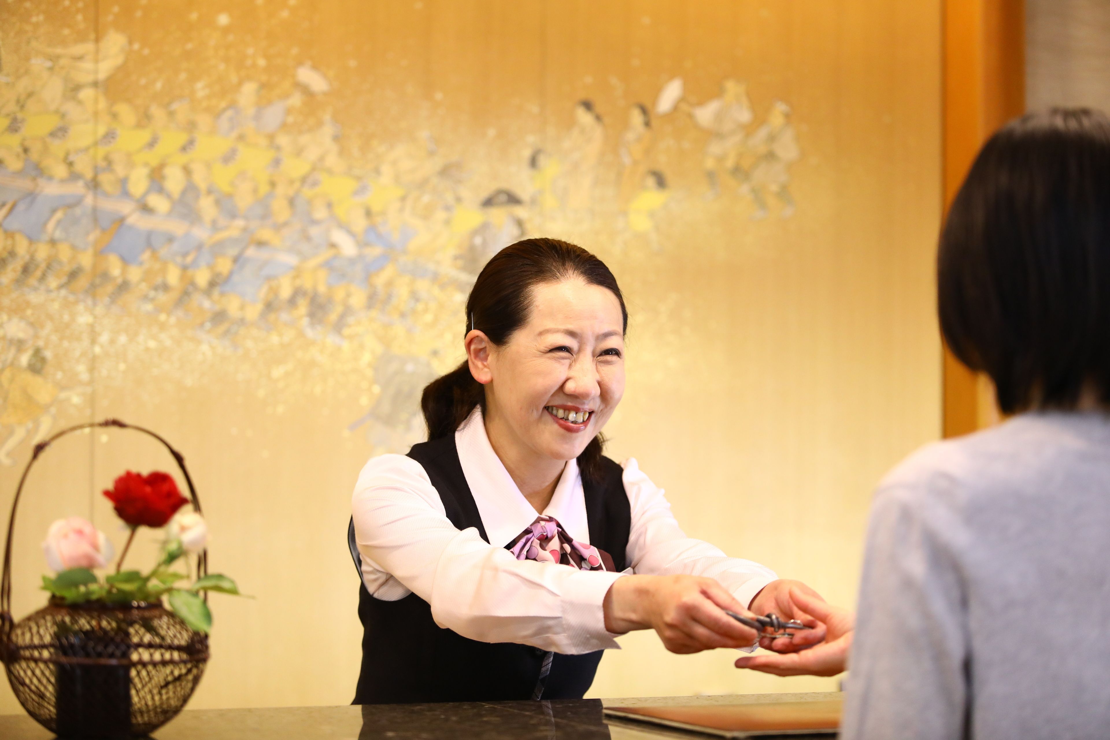 A reception area with a reception desk, a vase with flowers, and a decorative wall.