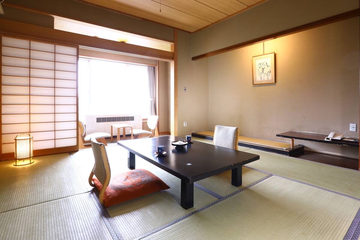 Una habitación japonesa tradicional con suelo de tatami, una mesa baja y paneles shoji.