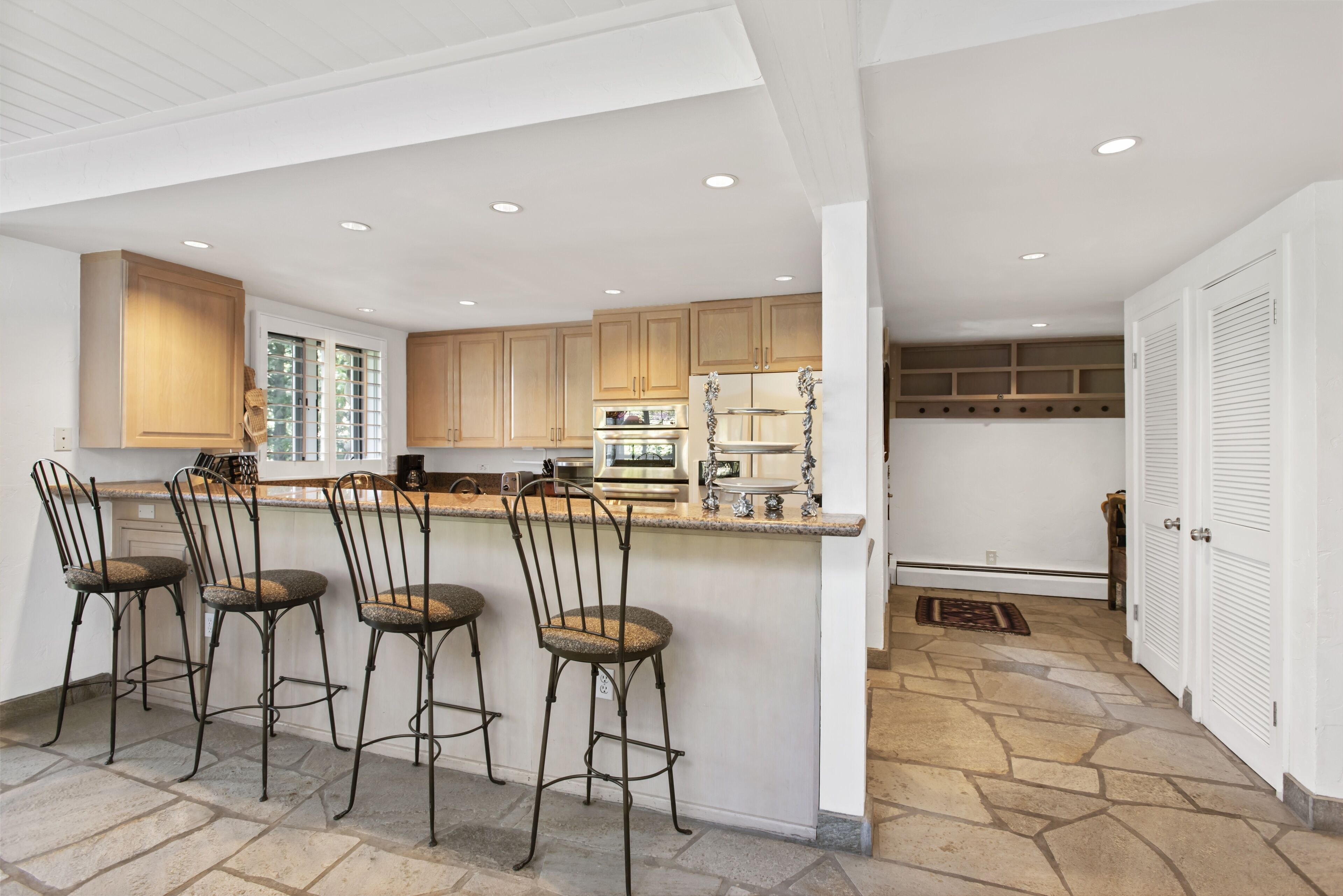 Una cucina moderna con isola centrale, sgabelli da bar e pensili in legno.