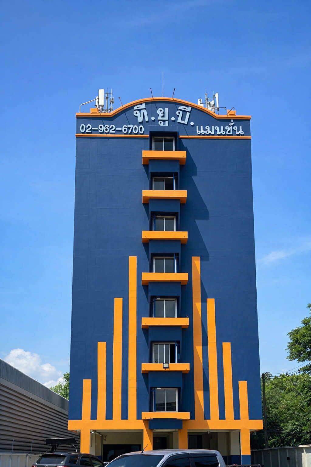 A tall building with a blue facade and orange accents, featuring a contact number and Korean text.