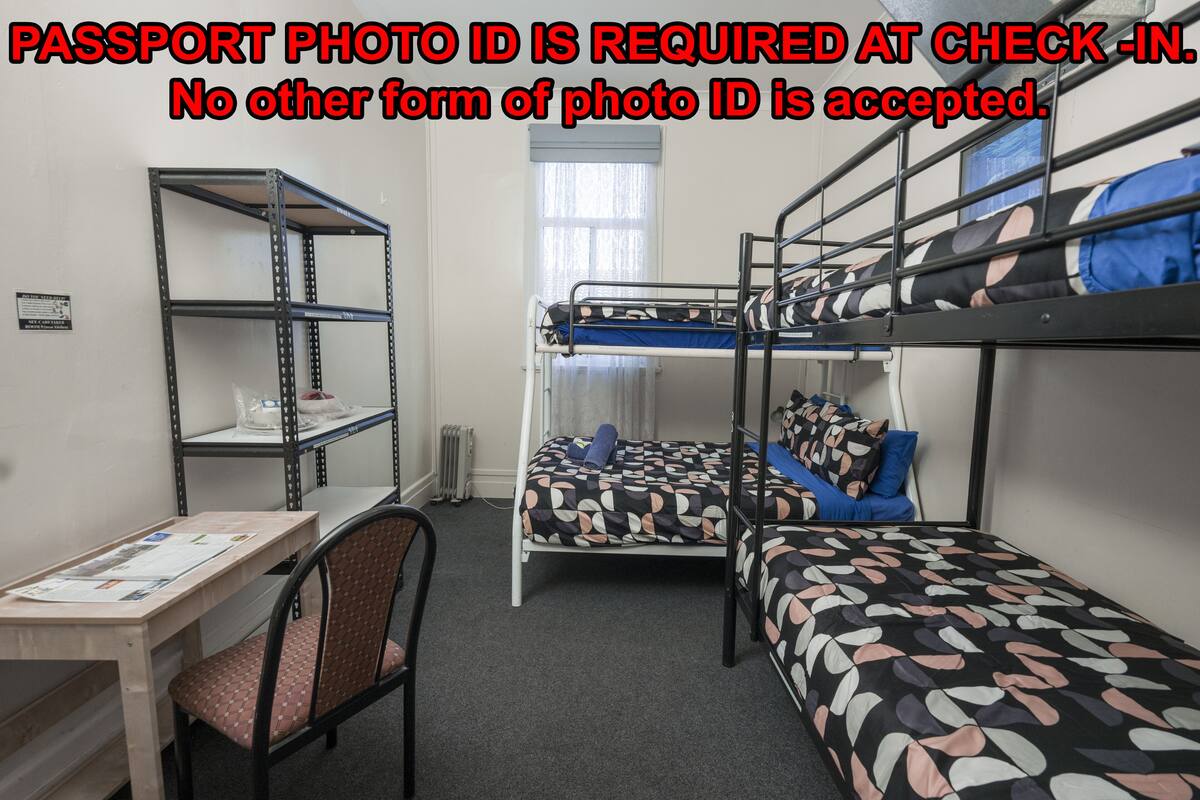 A dormitory room with bunk beds, a desk, and a chair.