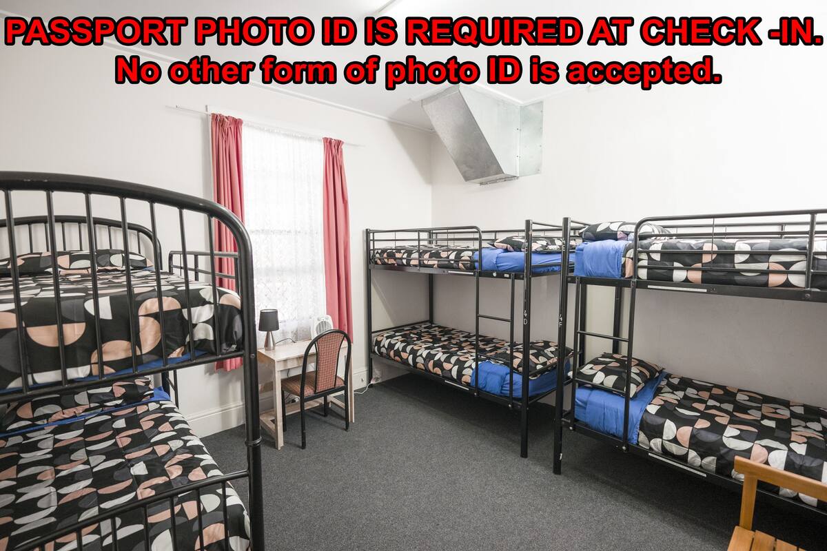 A dormitory room with bunk beds, a desk, and a chair.