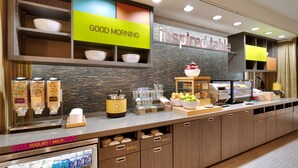 A breakfast bar with a 'Good Morning' sign, a 'Inspired Table' sign, and various food and drink dispensers. - Home2 Suites by Hilton Houston/Katy (Katy)