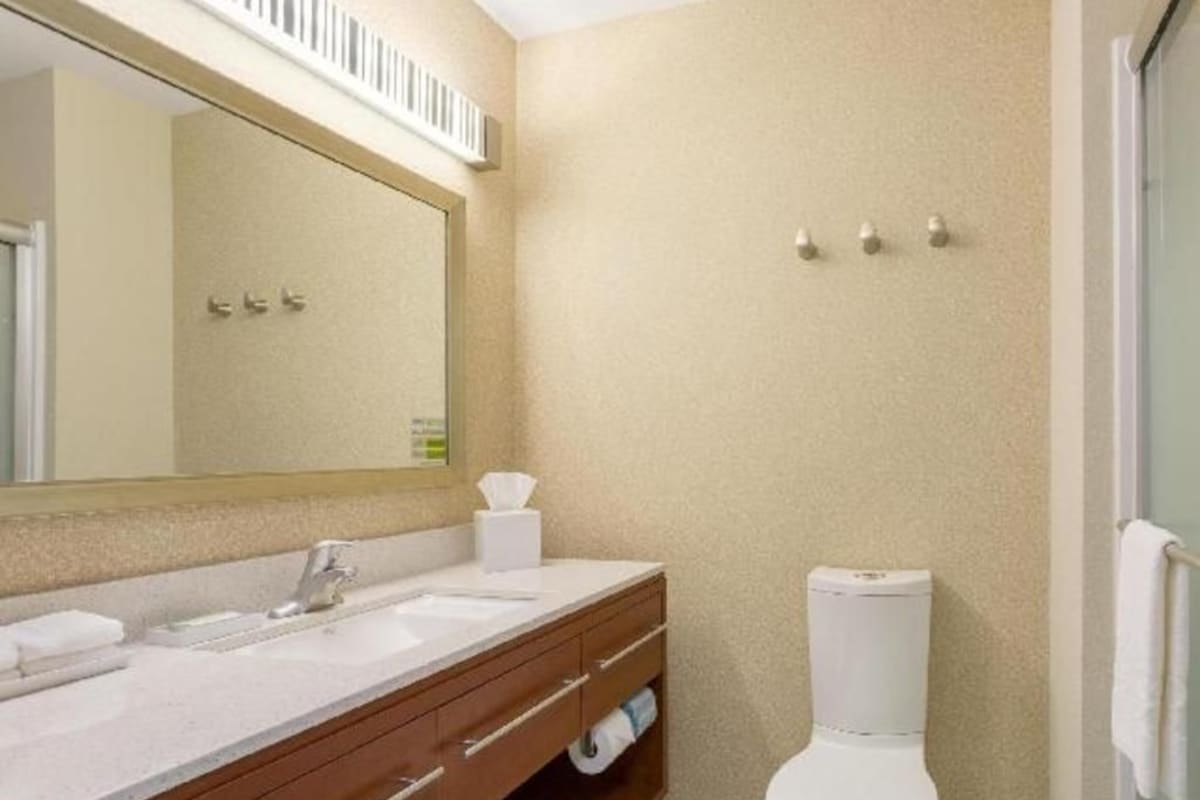 A bathroom with a white sink, mirror, and toilet.