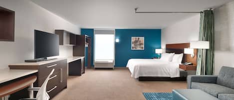 A hotel room with a bed, a desk with a TV, a chair, a sofa, and a window with curtains.