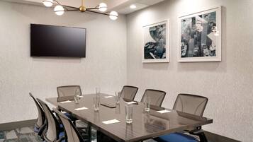 A conference room with a large table, chairs, a flat-screen TV, and framed pictures on the wall.