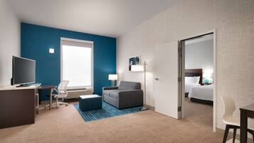 Una habitación de hotel con escritorio, silla, sofá y cama.