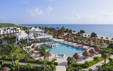 Un resort con piscina, sombrillas de playa y vistas al océano.