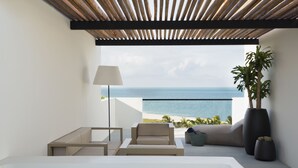 A modern outdoor seating area with a view of the ocean, a large potted plant, and a minimalist design. - Finest Playa Mujeres by The Excellence Collection - All Inclusive (Punta Sam)