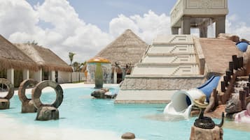 Relax by the resort pool, surrounded by thatched-roof huts and a large water slide.