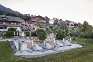 A resort with a pool area, outdoor seating, and a view of surrounding buildings and mountains. - Landhaus Ager (Soell)
