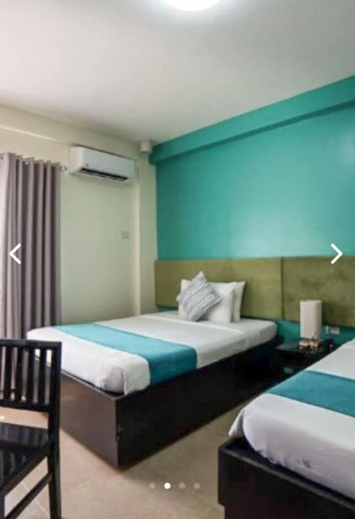 Une chambre d’hôtel avec deux lits, une chaise et un appareil de climatisation.