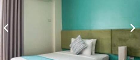Une chambre d’hôtel avec deux lits, une chaise et un appareil de climatisation.