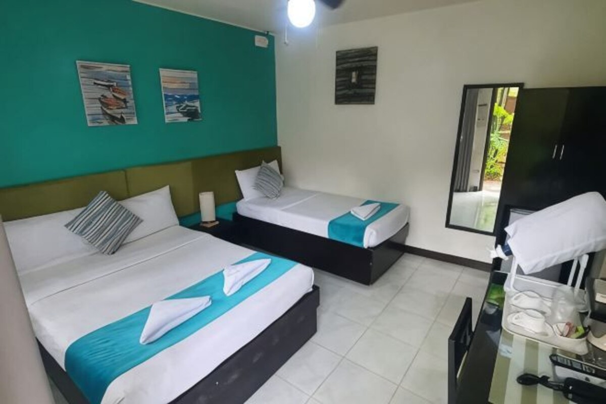 Una habitación de hotel con dos camas, un escritorio y un espejo.